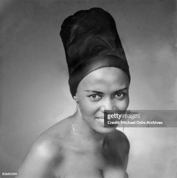 Smiling person with a tall headwrap against a soft, gray background. Image has a calm, confident mood. Visible text: Getty Images.